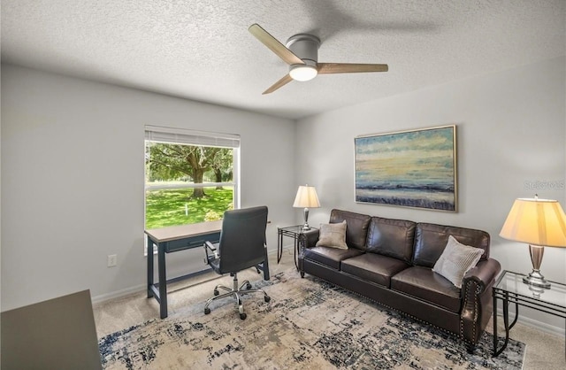 carpeted home office with ceiling fan and a textured ceiling