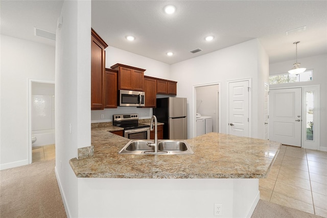 kitchen featuring washer and dryer, stainless steel appliances, kitchen peninsula, and light colored carpet