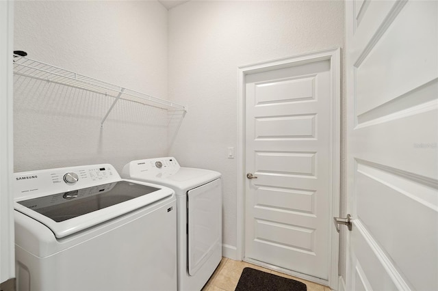 laundry area with washing machine and dryer and light tile patterned floors