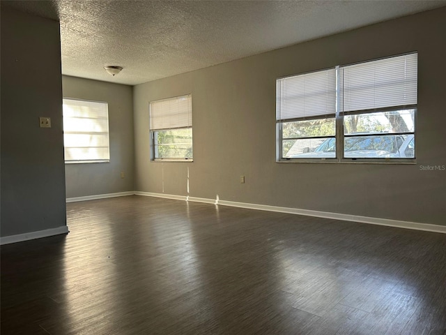 unfurnished room with a textured ceiling and dark hardwood / wood-style floors