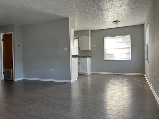 unfurnished living room featuring a textured ceiling and dark hardwood / wood-style floors