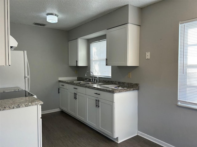 kitchen featuring white cabinets, white fridge, sink, and dark wood-type flooring