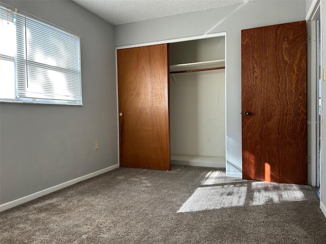 unfurnished bedroom featuring a textured ceiling, carpet floors, and a closet