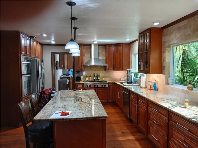 kitchen featuring a center island, a kitchen breakfast bar, wall chimney range hood, decorative light fixtures, and dark hardwood / wood-style flooring