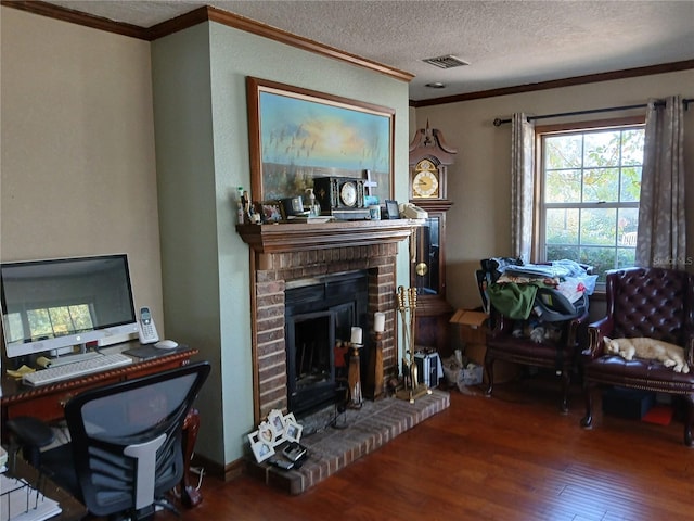 living room featuring hardwood / wood-style floors, ornamental molding, a fireplace, and a textured ceiling