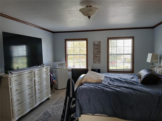 bedroom featuring multiple windows, light hardwood / wood-style flooring, a textured ceiling, and ornamental molding