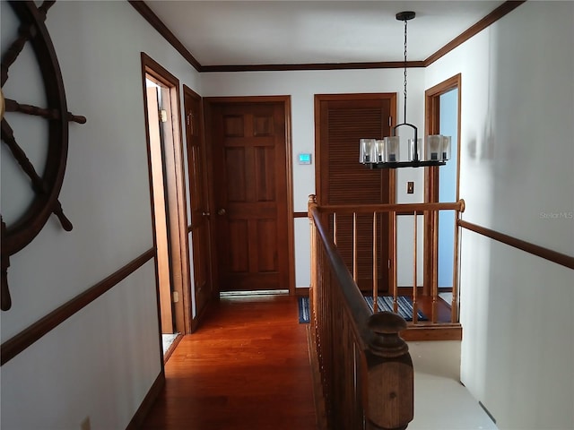 hall featuring crown molding, dark wood-type flooring, and a notable chandelier