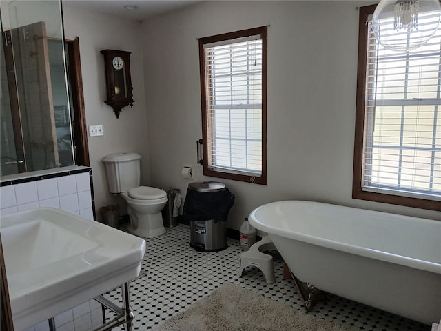 bathroom featuring toilet, a bath, and tile patterned floors