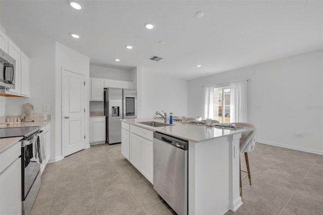 kitchen featuring appliances with stainless steel finishes, white cabinetry, sink, and an island with sink