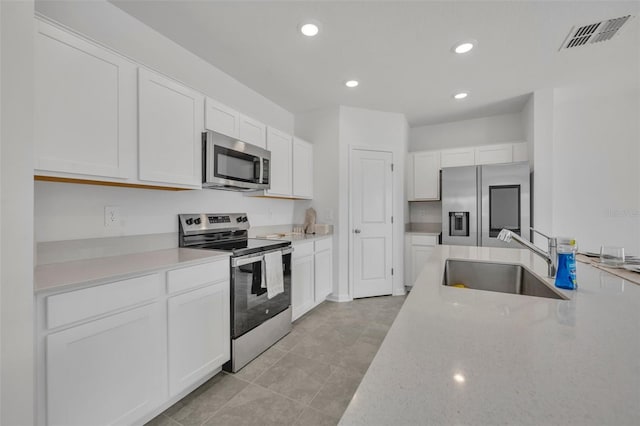 kitchen featuring light tile patterned floors, appliances with stainless steel finishes, sink, and white cabinets