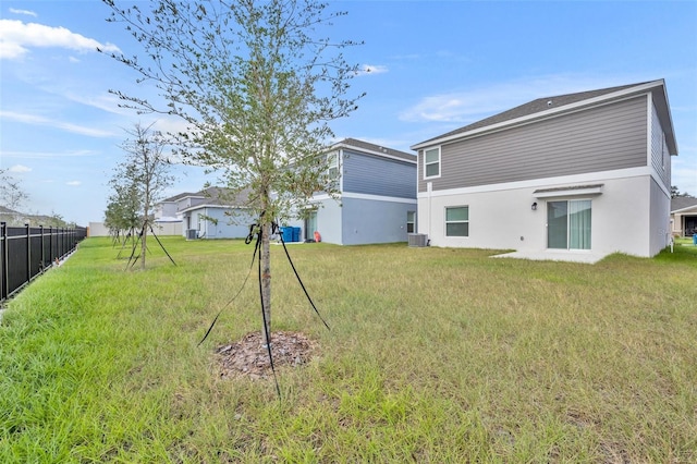 rear view of property with central AC and a lawn