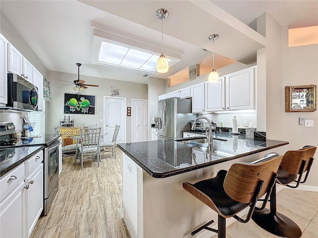 4088 Kingsley St, Clermont, FL 34711 - kitchen with a breakfast bar, a peninsula, stainless steel appliances, and white cabinetry