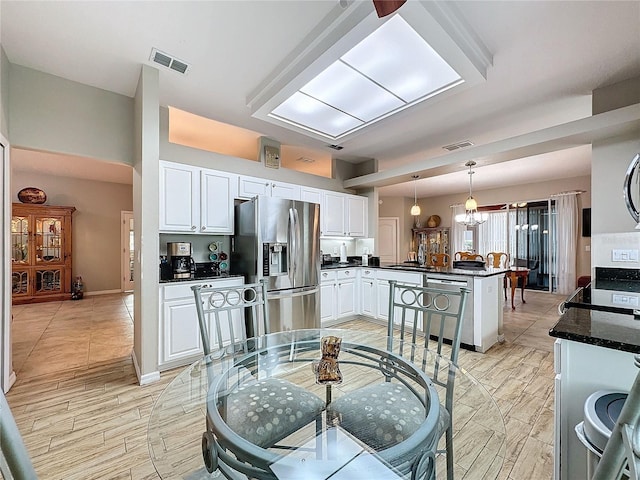 4088 Kingsley St, Clermont, FL 34711 - kitchen with a peninsula, stainless steel appliances, visible vents, white cabinetry, and a notable chandelier