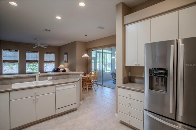 kitchen featuring dishwasher, sink, stainless steel fridge, white cabinetry, and pendant lighting