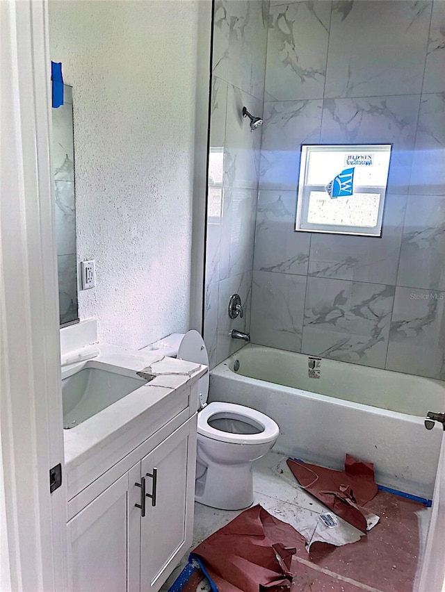 full bathroom with tiled shower / bath, vanity, and toilet