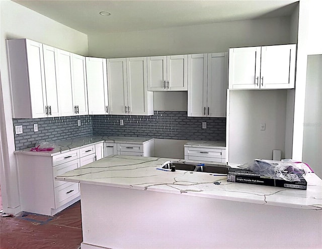 kitchen with white cabinets, tasteful backsplash, light stone countertops, dark hardwood / wood-style floors, and sink