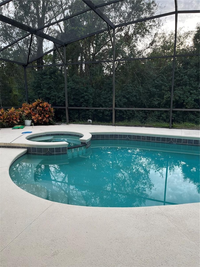 view of swimming pool with an in ground hot tub and glass enclosure