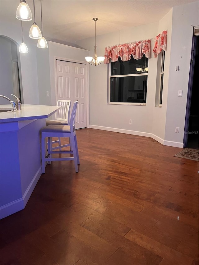 kitchen with sink, a kitchen breakfast bar, dark hardwood / wood-style flooring, and hanging light fixtures