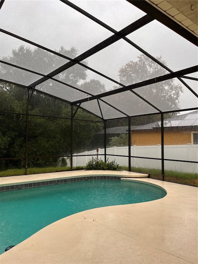 view of pool with glass enclosure and a patio