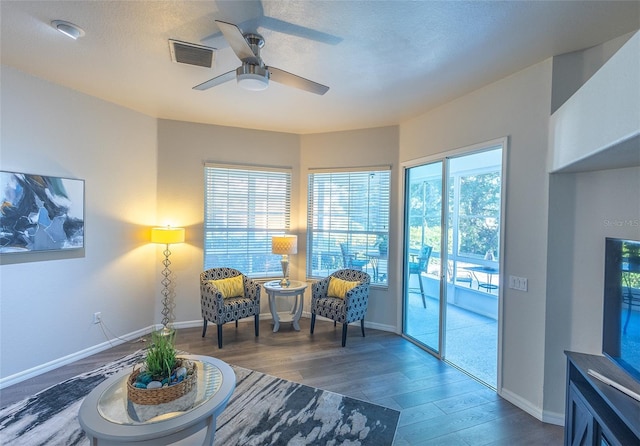 living area featuring ceiling fan, plenty of natural light, dark wood-type flooring, and a textured ceiling