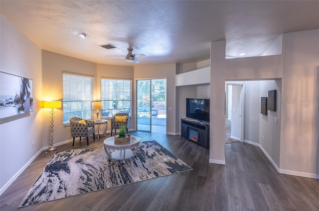 living room featuring dark hardwood / wood-style floors, ceiling fan, and a textured ceiling