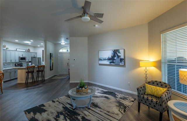 living room with ceiling fan and dark hardwood / wood-style flooring