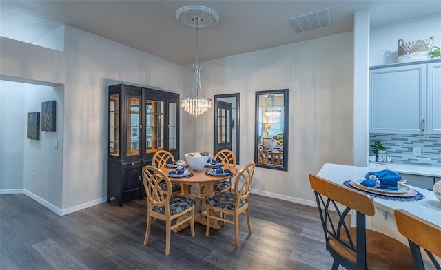 dining area featuring dark hardwood / wood-style flooring and an inviting chandelier