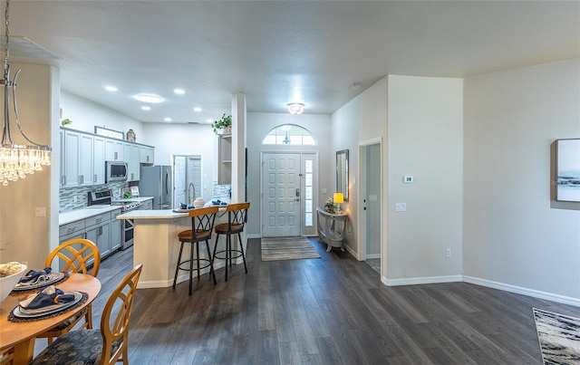 kitchen with a kitchen bar, backsplash, stainless steel appliances, sink, and dark hardwood / wood-style floors