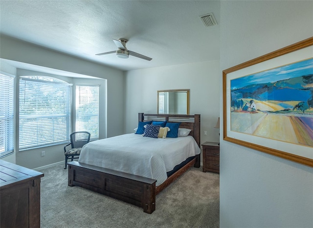 carpeted bedroom with ceiling fan and a textured ceiling