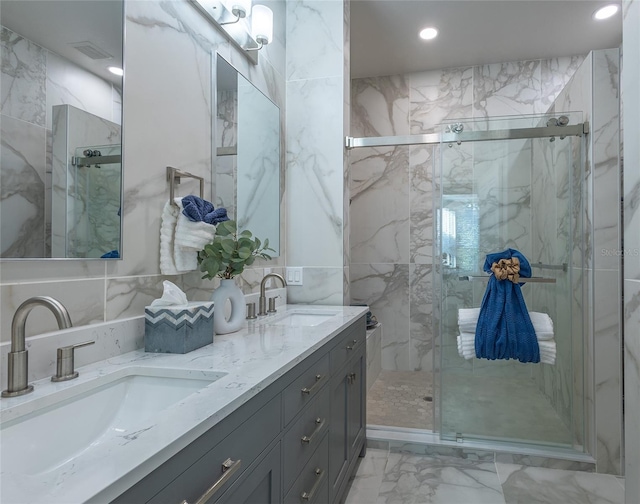 bathroom featuring a shower with door, vanity, and tile walls