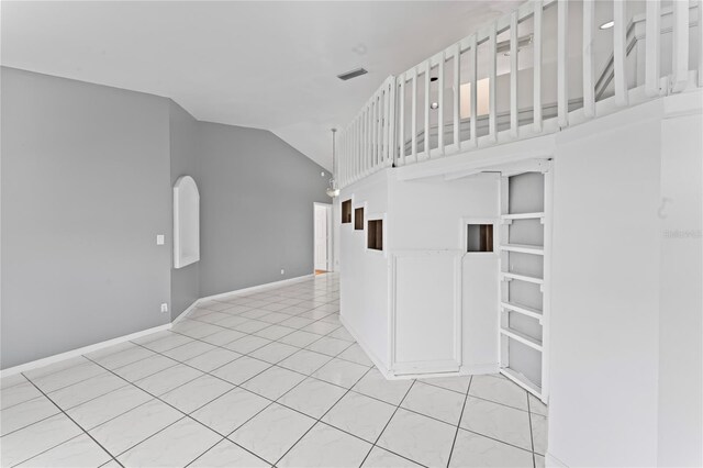 unfurnished living room with high vaulted ceiling and light tile patterned floors