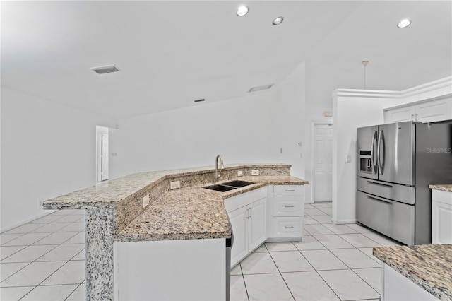 kitchen with white cabinets, a kitchen island with sink, sink, and stainless steel fridge