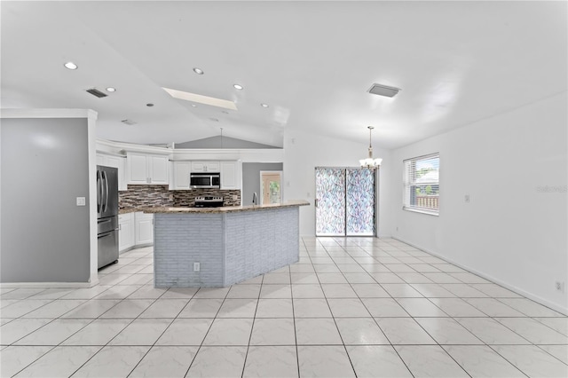 kitchen featuring white cabinets, appliances with stainless steel finishes, vaulted ceiling, light tile patterned flooring, and a notable chandelier