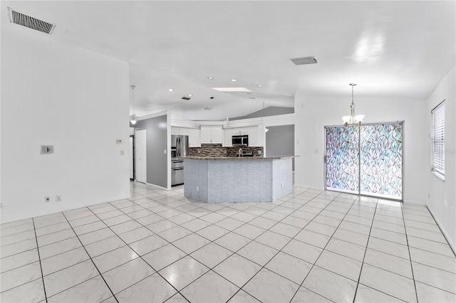 kitchen featuring tasteful backsplash, light tile patterned flooring, vaulted ceiling, white cabinets, and a chandelier