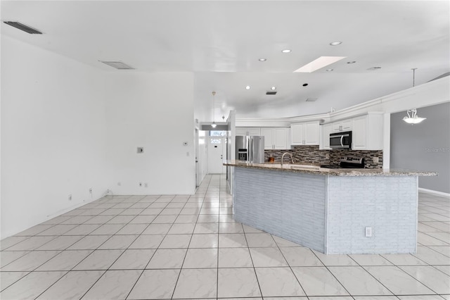 kitchen featuring white cabinets, tasteful backsplash, appliances with stainless steel finishes, a skylight, and light stone counters