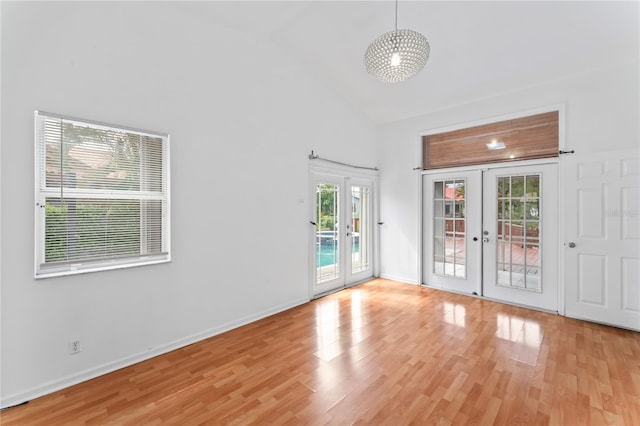 spare room with light hardwood / wood-style flooring, french doors, and high vaulted ceiling