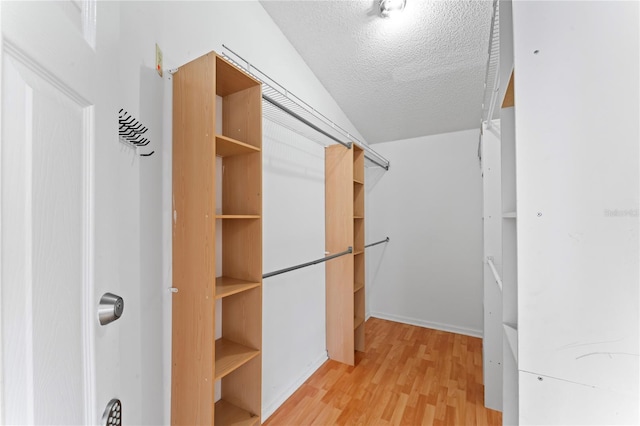 walk in closet featuring vaulted ceiling and light wood-type flooring