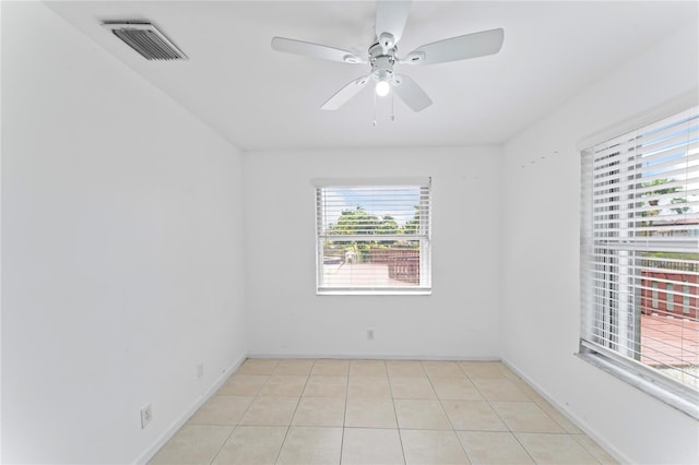 empty room featuring a wealth of natural light, ceiling fan, and light tile patterned floors