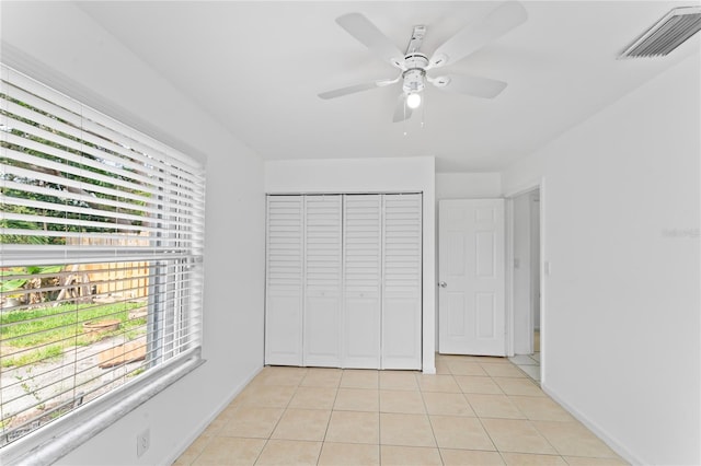 unfurnished bedroom with a closet, ceiling fan, and light tile patterned floors