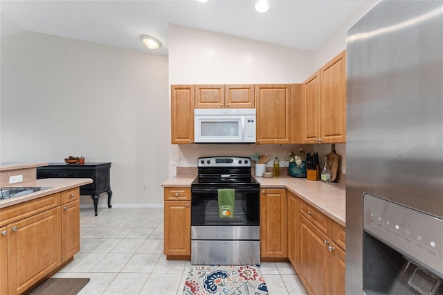 kitchen with appliances with stainless steel finishes, light tile patterned floors, and vaulted ceiling