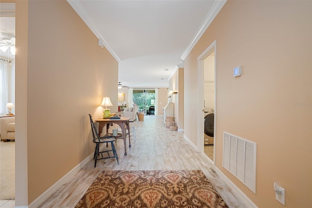 hall featuring washer / clothes dryer, ornamental molding, and light hardwood / wood-style flooring