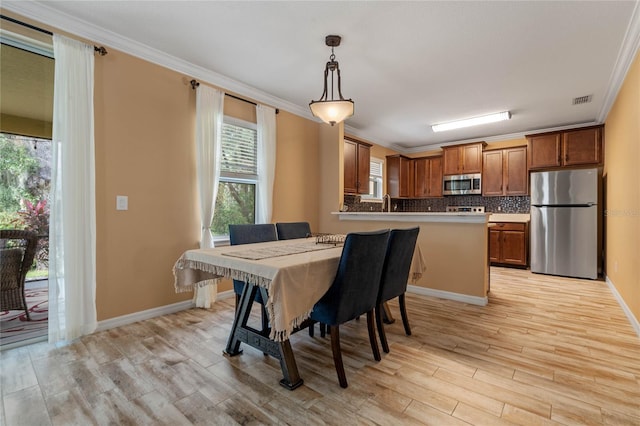 dining space with a wealth of natural light, crown molding, and light hardwood / wood-style flooring