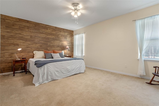 bedroom featuring light carpet, wooden walls, and ceiling fan