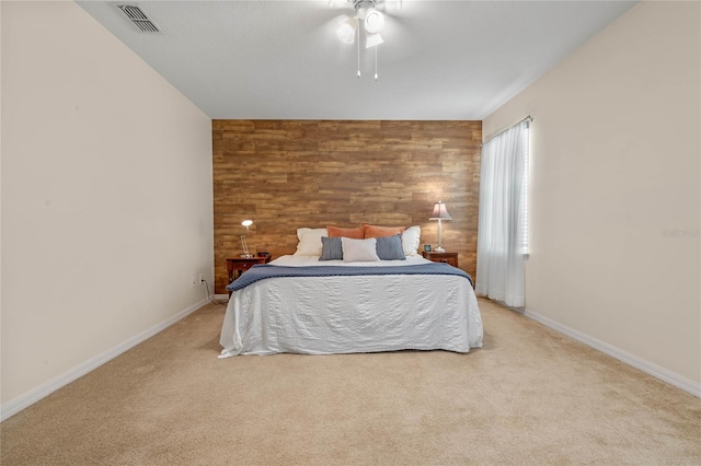 bedroom with light carpet, wood walls, and ceiling fan