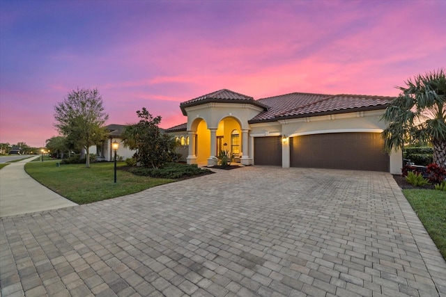 mediterranean / spanish house with a garage and a lawn