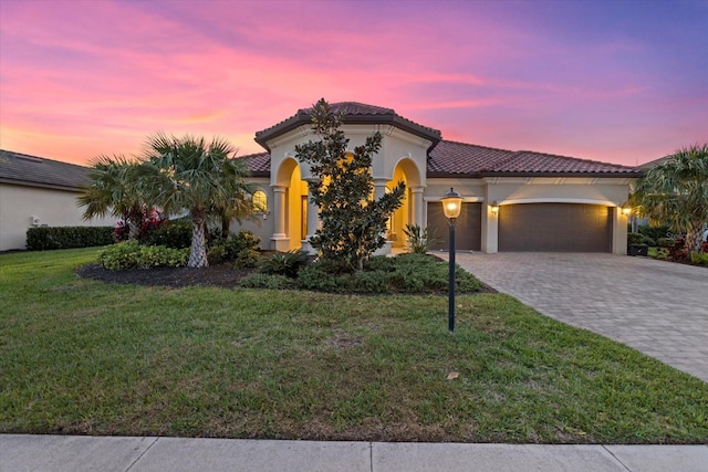 mediterranean / spanish-style house with a garage and a lawn