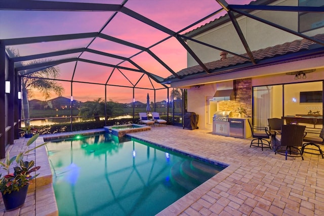 pool at dusk with area for grilling, an outdoor kitchen, an in ground hot tub, a patio, and glass enclosure