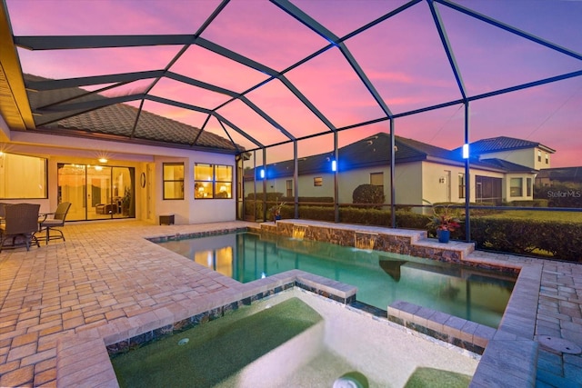 pool at dusk featuring an in ground hot tub, a patio, and a lanai