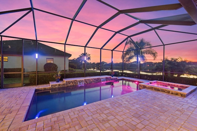 pool at dusk with a patio, an in ground hot tub, and glass enclosure