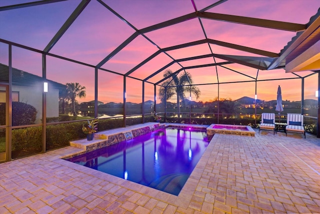 pool at dusk with a patio, an in ground hot tub, and a lanai